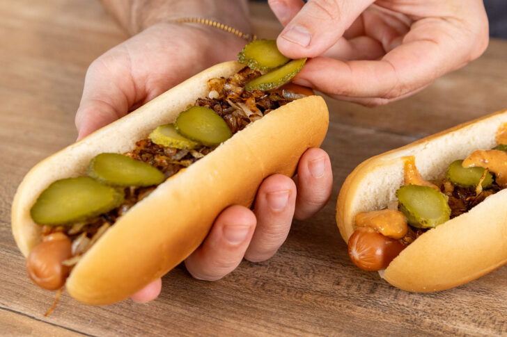Gurke auf den Hot Dog geben