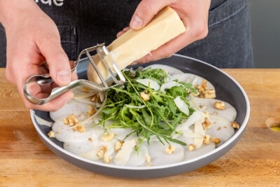 Käse über das Kohlrabi-Carpaccio hobeln