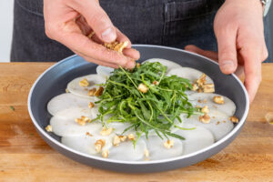 Angeröstete Walnüsse über das Kohlrabi Carpaccio geben
