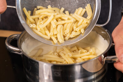 Nudeln in die Käsesauce geben