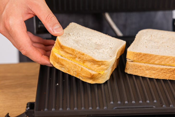 Toastscheiben mit Cheddar in den Kontaktgrill geben