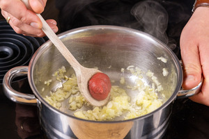 Tomatenmark zur Zwiebel in den Topf geben