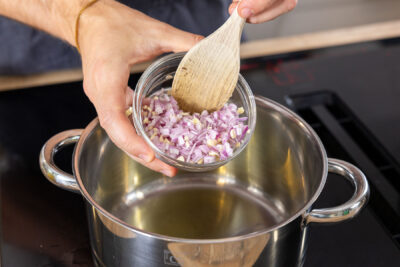 Schalotte und Knoblauch in den Topf geben