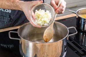 Zwiebelwürfel in den Topf geben