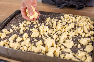 Streusel über dem Mohnkuchen verteilen