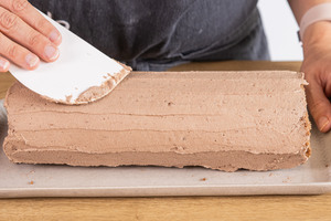 Schoko-Biskuitrolle mit Creme dekorieren