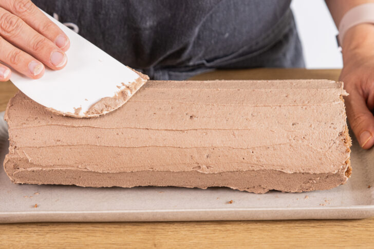 Schoko-Biskuitrolle mit Creme dekorieren