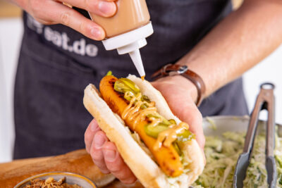 Sauce auf vegetarischem Möhren-Hot-Dog verteilen