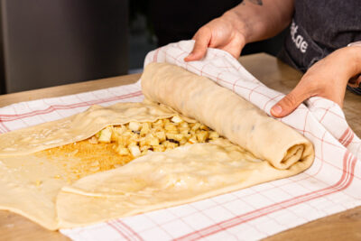 Apfelstrudel mithilfe eines Küchentuchs aufrollen