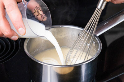 Brühe und Milch in die Mehlschwitze rühren