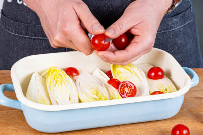 Kirschtomaten halbieren und in die Auflaufform geben