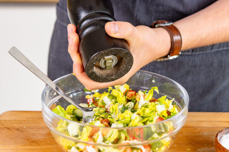 Salat mit Pfeffer würzen