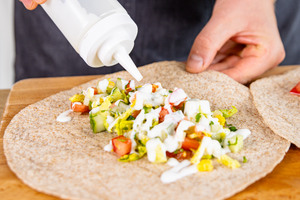 Salatsoße über Salat geben