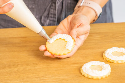 Buttercreme auf Plätzchen mit einem Spritzbeutel auftragen