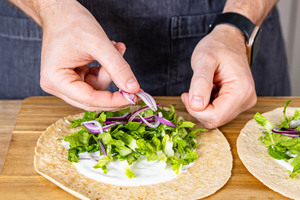 Salat und Zwiebel auf Tortilla verteilen