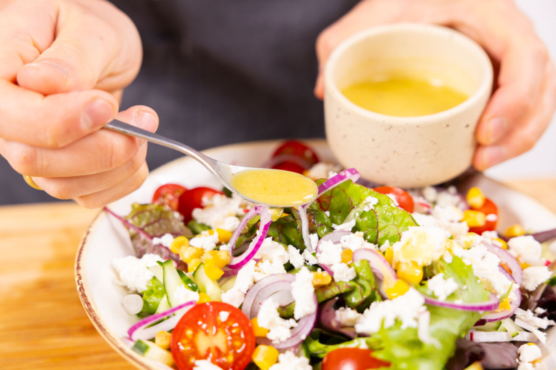 Dressing über Salat geben