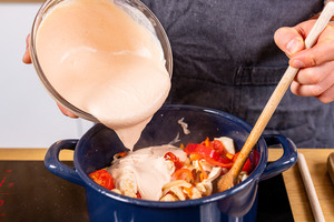 Soße über Fleisch und Gemüse in den Topf geben