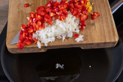 Zwiebeln, Knoblauch, Paprika und Chili in der Pfanne erhitzen