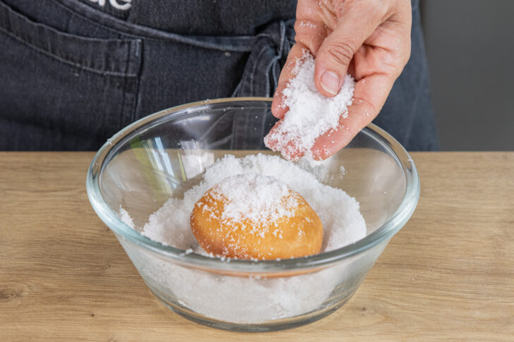 Krapfen mit Zucker bestreuen