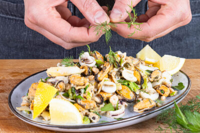 Meeresfrüchtesalat mit Dill und Petersilie verfeinern