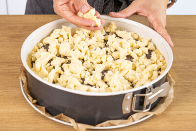 Butterstreusel auf dem Mohnkuchen mit Pudding verteilen