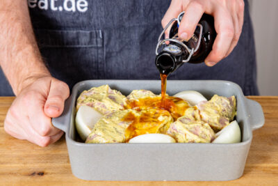 mariniertes Fleisch in einer Auflaufform mit Schwarzbier aufgießen