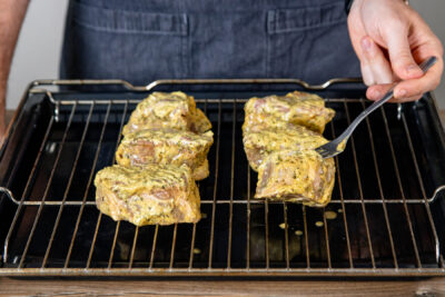 mariniertes Fleisch für Mutzbraten auf einem Rost über einem tiefen Blech platzieren