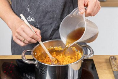 Gemüsebrühe zur Orzo gießen