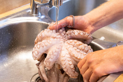 Pulpo unter fließendem Wasser reinigen