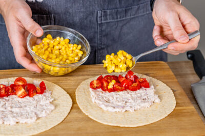 Tomaten und Mais auf Thunfisch-Wraps verteilen