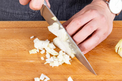 Zwiebel und Knoblauch in kleine Würfel schneiden