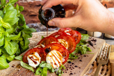 Selbst gemachte Balsamico Creme über Caprese geben