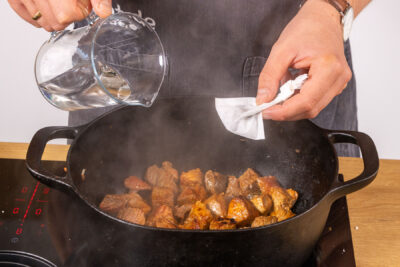 Wasser und Gewürzbeutel zum Fleisch geben