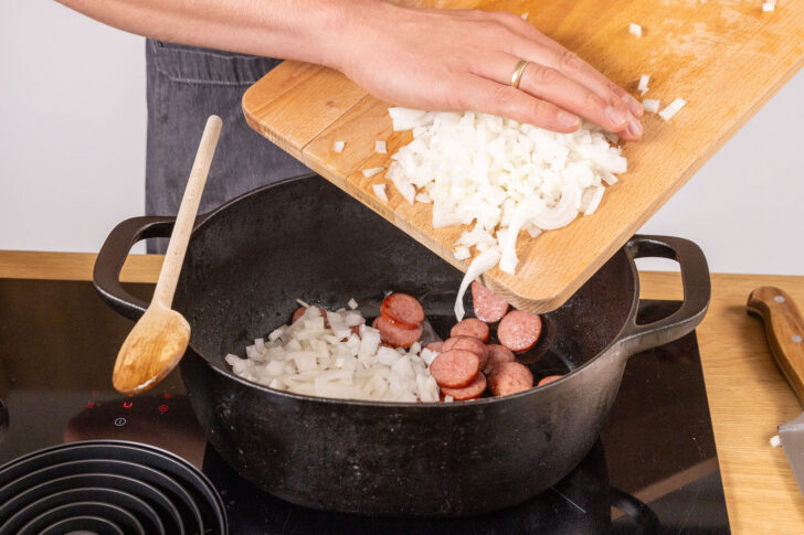 Zwiebel zur Cabanossi in den Bräter geben