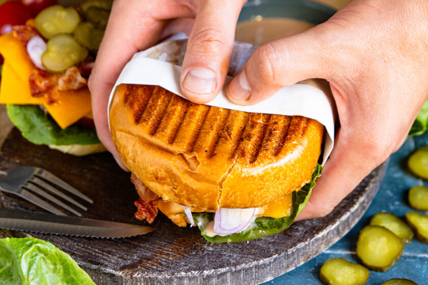 Cheeseburger vom Kontaktgrill in den Händen gehalten