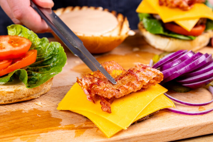 Burgerpatty mit Käse und Bacon belegen
