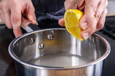 Für den Sirup die Zitrone in den Topf geben.