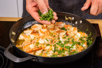 frische gehackte Petersilie über Gambas al Ajillo geben