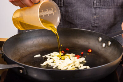 Olivenöl über Knoblauch und Chilis geben