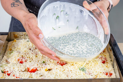 Schmand-Guss über Gemüsekuchen verteilen