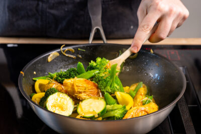 Hähnchen und Gemüse in der Pfanne vermischen