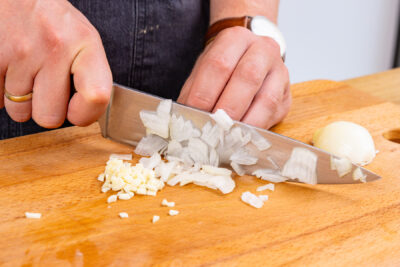 Zwiebel und Knoblauch in Würfel schneiden
