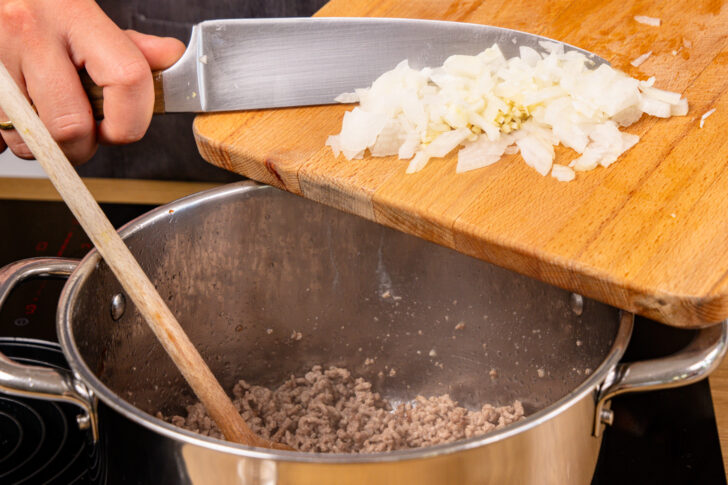 Zwiebel und Knoblauch zum Hackfleisch geben