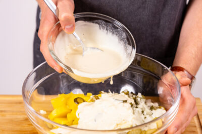Mayonnaise-Dressing zum Kartoffelsalat geben