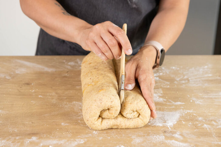 Marzipanstollen in der Mitte mit Wasser einstreichen