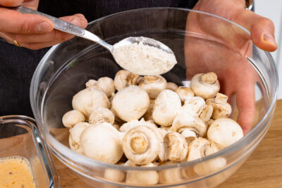 Champignons in Schüssel bemehlen