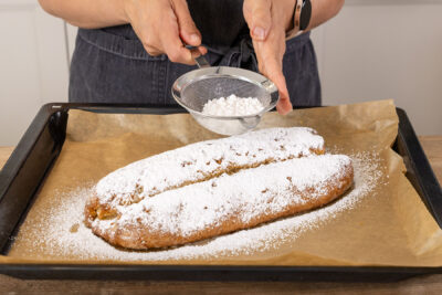 Mandelstollen mit Puderzucker bestäuben