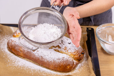 Saftigen Marzipanstollen mit Puderzucker bestreuen