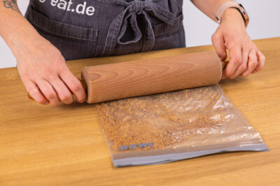 Spekulatiuskekse in Beutel mit Nudelholz zerkleinern