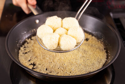 Topfenknödel in Zucker-Semmelbrösel-Mischung wälzen